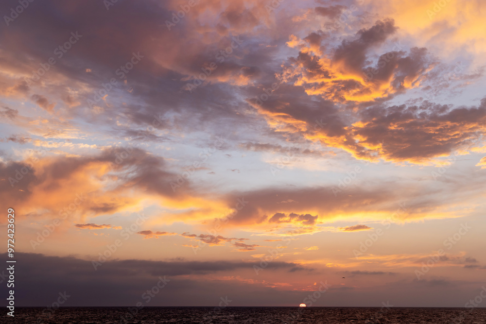 A dramatic and moody sunset sky filled with dark, swirling clouds A dramatic and moody sunset sky filled with dark, swirling clouds