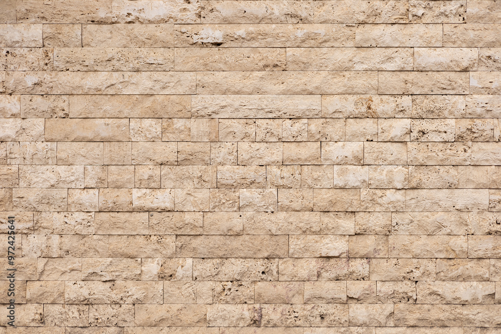 Textured beige stone wall with rectangular blocks in a modern architectural setting Textured beige stone wall with rectangular blocks in a modern architectural setting