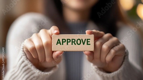 Close-up of a person holding a wooden block with the word 'Approve' written on it, symbolizing consent, agreement, or positive feedback. photo