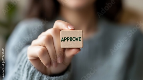 Close-up of a person holding a wooden block with the word 'Approve' written on it, concept of approval or confirmation. photo