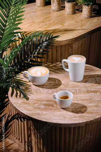 Three cups of coffee sitting on a table with a palm tree in the background