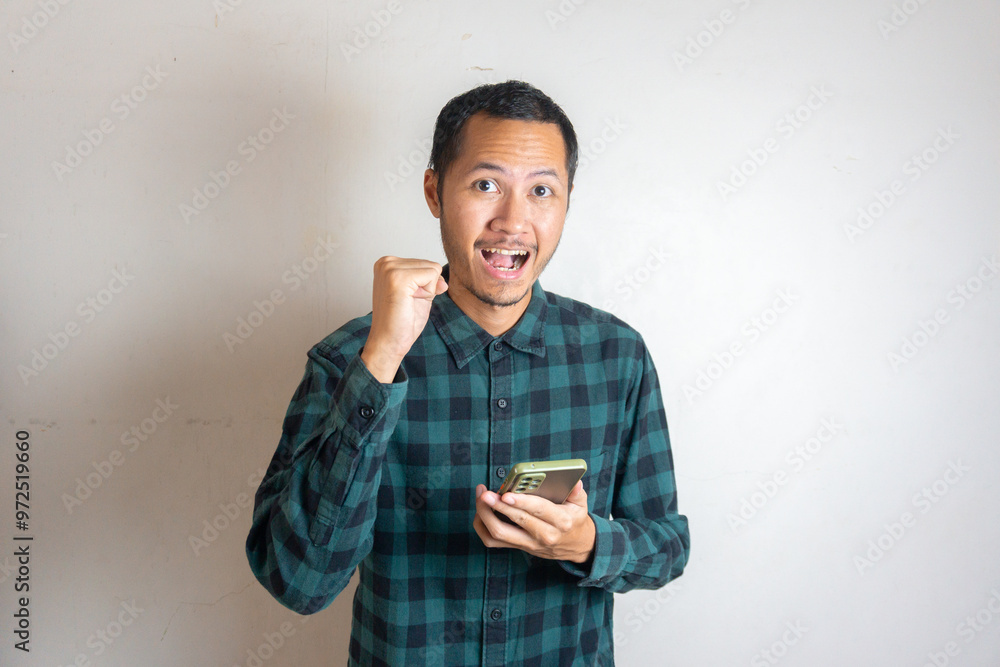 Young asian men is holding smartphone with happy expression in isolated white background Young asian men is holding smartphone with happy expression in isolated white background