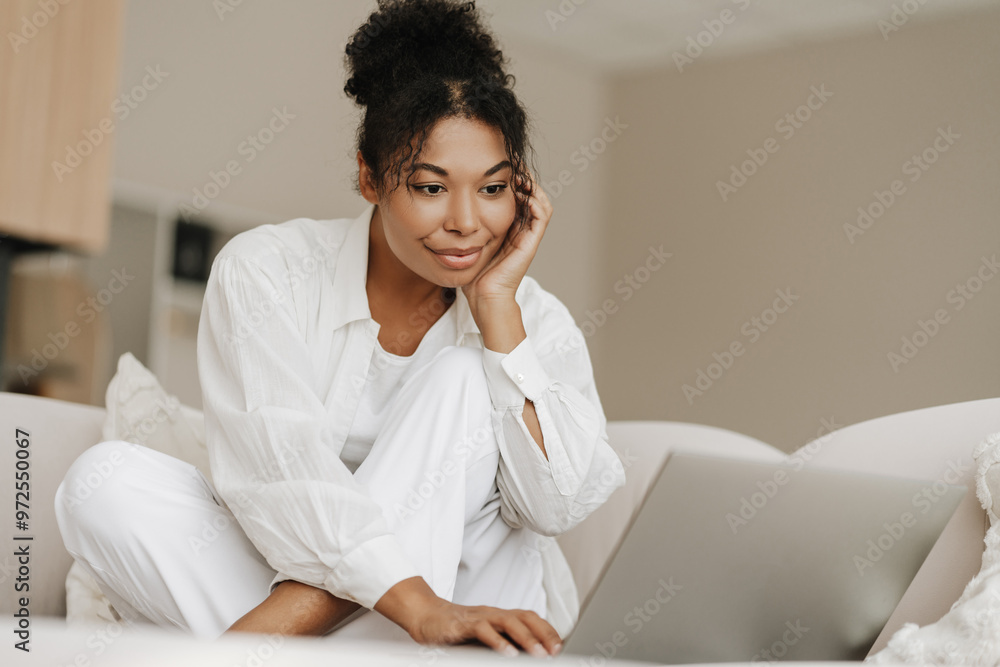 Young woman sitting on couch using laptop computer at home Young woman sitting on couch using laptop computer at home