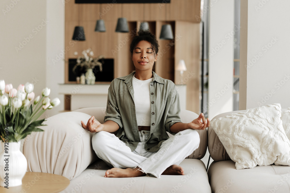Young woman meditating sitting in lotus pose on sofa at home Stock ...
