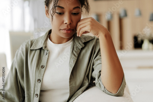 Young woman feeling sad while sitting on sofa at home photo