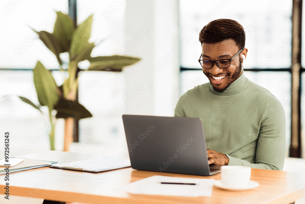 Distance Education. Happy black student using laptop in university cafe wearing wireless headphones, copy space Distance Education. Happy black student using laptop in university cafe wearing wireless headphones, copy space