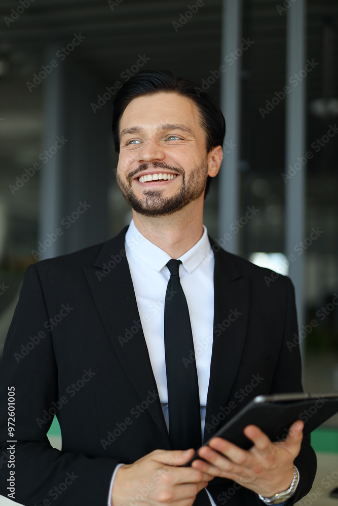 A man in a suit and tie is smiling and holding a tablet. He is happy and confident A man in a suit and tie is smiling and holding a tablet. He is happy and confident