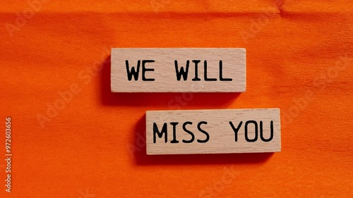 We will miss you message writing on wooden blocks on orange background. Conceptual we will miss you symbol.