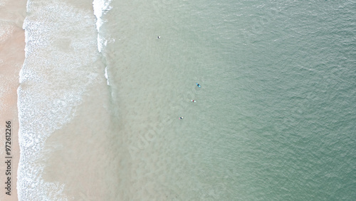    Surfers catching waves, waiting for a wave to come in the middle of the ocean near the beach during a beautiful day