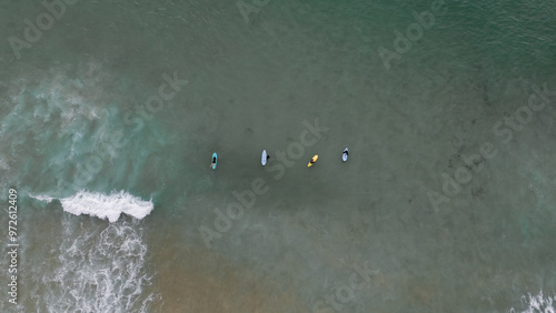    Surfers catching waves, waiting for a wave to come in the middle of the ocean near the beach during a beautiful day