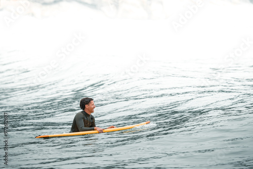    Surfers catching waves, waiting for a wave to come in the middle of the ocean near the beach during a beautiful day