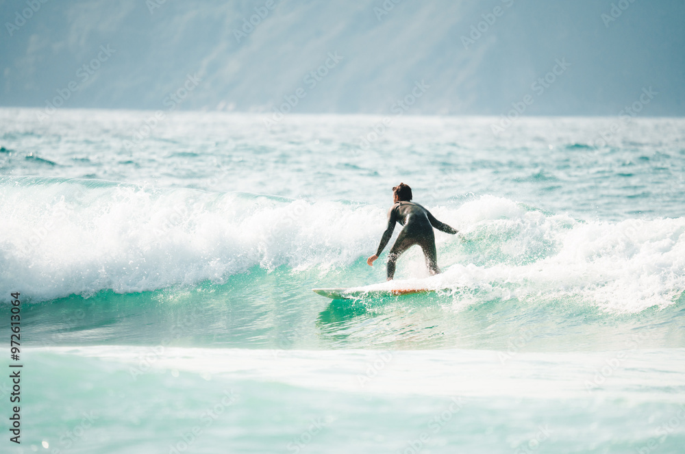 Surfers catching waves, waiting for a wave to come in the middle of the ocean near the beach during a beautiful day Surfers catching waves, waiting for a wave to come in the middle of the ocean near the beach during a beautiful day