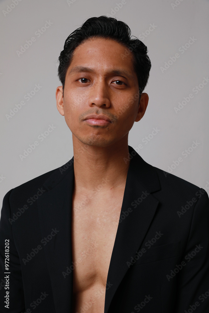 Obraz premium Vertical portrait of young asian man posing over white background. Vertical.