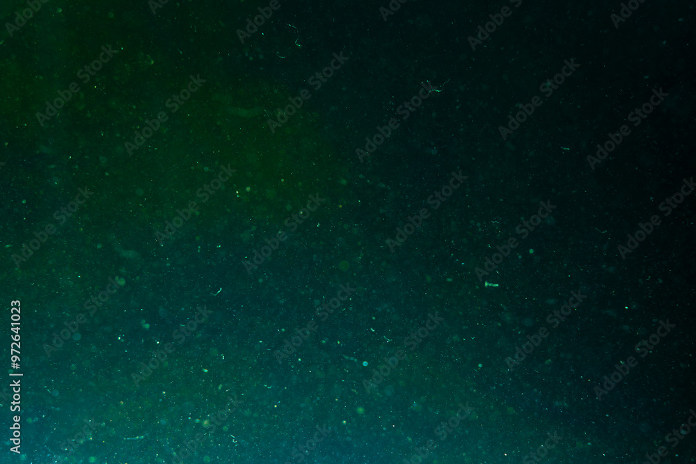 Abstract water background with dark green glow Chaotically moving glowing dust particles in water. Underwater. Macro world. Textured. Wallpaper Abstract water background with dark green glow Chaotically moving glowing dust particles in water. Underwater. Macro world. Textured. Wallpaper