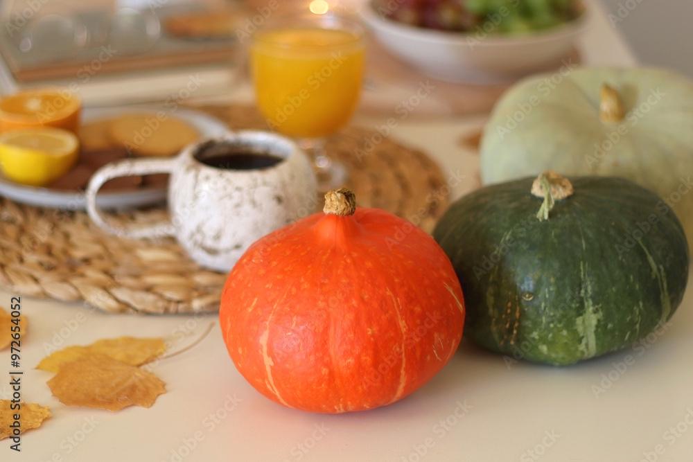 Pumpkins, various food and drinks, fall decorations, books and candles on the table. Fall hygge at home. Selective focus. Pumpkins, various food and drinks, fall decorations, books and candles on the table. Fall hygge at home. Selective focus.