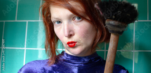 Portrait of a nice woman in a bathroom with broomerstick in hand, funny concept glamour housekeeping