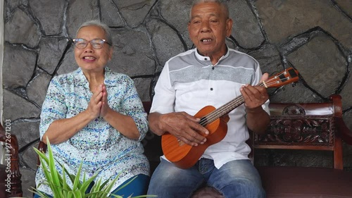 Happy Asian Elderly Couple With Daughter Playing Ukulele Guitar And Singing Together At Home photo