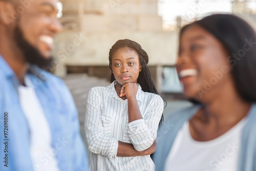 Fototapeta Upset black woman watching her ex boyfriend happy in relations with new girlfrie