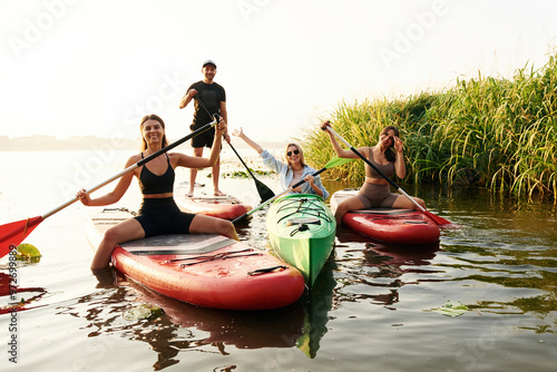 Obraz na plátně Women and man. Friends are together on sup boards on the lake