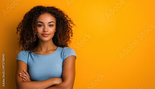 Confident young woman with curly hair smiling against a bright yellow background.