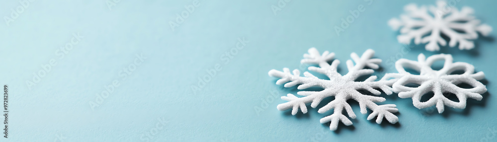 Three delicate white snowflakes on a soft blue background, capturing the beauty of winter and the charm of the snowy season. Three delicate white snowflakes on a soft blue background, capturing the beauty of winter and the charm of the snowy season.