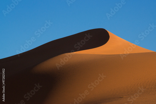 Graphic line of a red dune creating strong contrasts between light and shadow on the background of the blue sky, namib naukluft national park, namibia