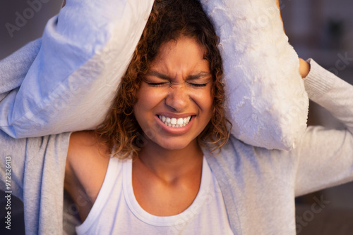 Angry student girl trying to sleep, covering ears with pillows and closing eyes, irritated with annoying sound photo