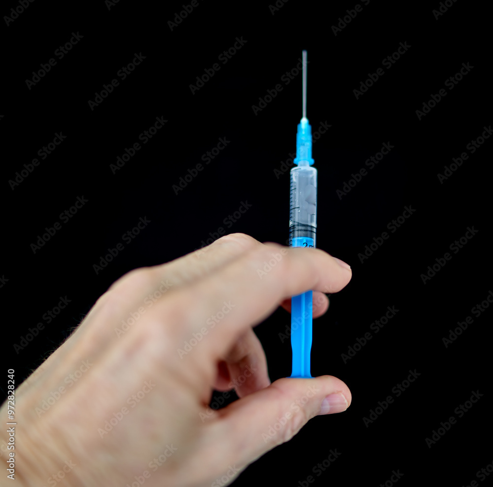 a fragment of a human hand holds a syringe a fragment of a human hand holds a syringe
