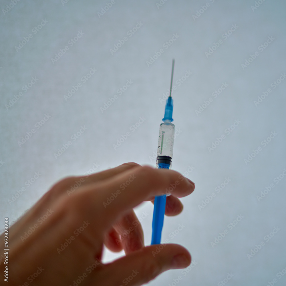 a fragment of a human hand holds a syringe a fragment of a human hand holds a syringe