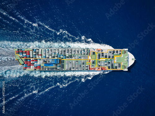Aerial top down view of a large, industrial car carrier transport ship cruising with peed over the ocean © moofushi