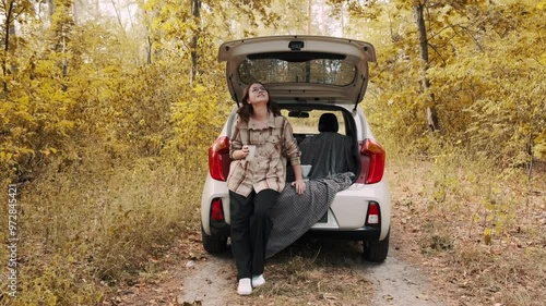 Young girl drinking coffee in the car. Filter coffee to go. Cup of tea or coffee. Car trip. Autumn atmosphere. Autumn