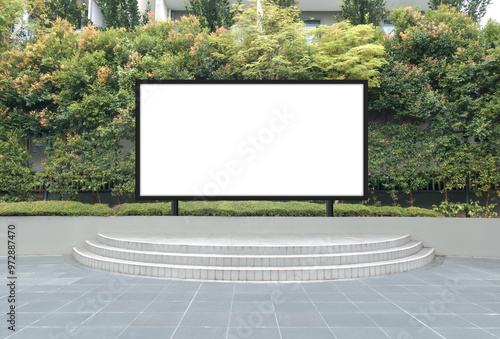 Mock up template: Horizontal billboard out of home (OOH) advertising poster on sidewalk, against background of lush plants. Poster frame is installed on concrete stage with steps. Transparent png file