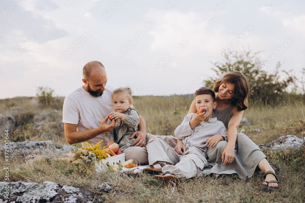 Happy Family Enjoying a Picnic in a Scenic Field with Fresh Fruits and Nature