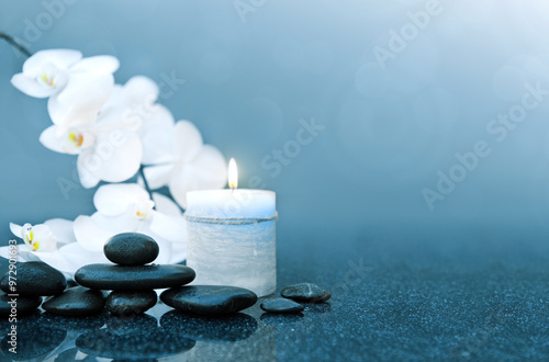 Spa background with white orchid , candle and zen black stones on gray.