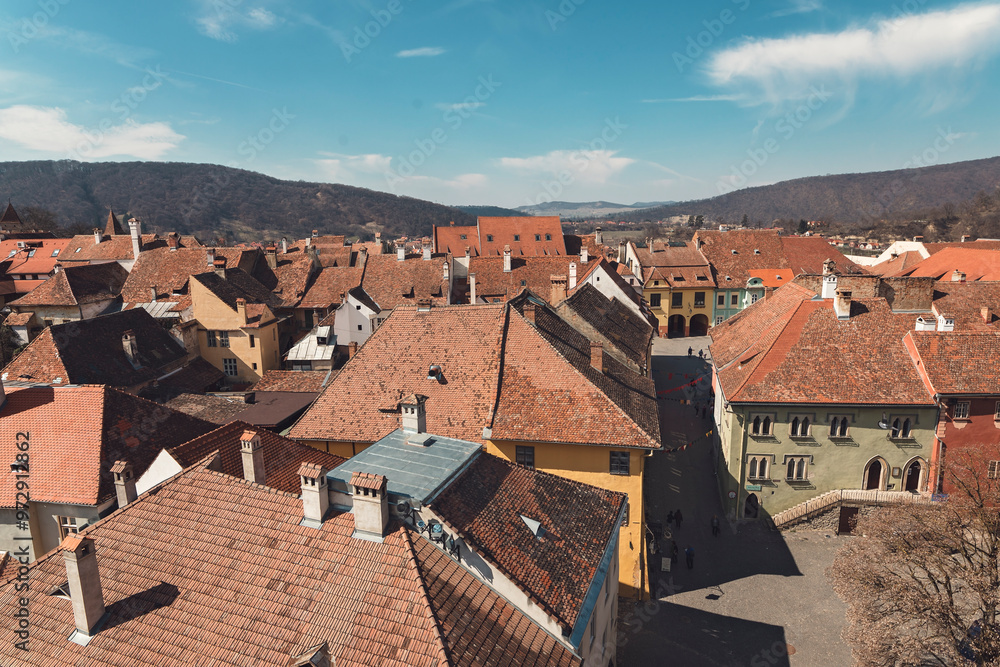 Roofs of quaint houses showcase a blend of colors and styles, set against a backdrop of rolling hills and a brilliant blue sky, inviting exploration and wonder Roofs of quaint houses showcase a blend of colors and styles, set against a backdrop of rolling hills and a brilliant blue sky, inviting exploration and wonder