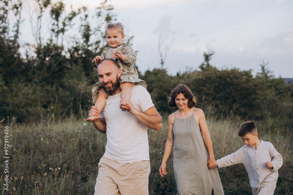 Happy Family Enjoying Outdoor Walk in Nature with Father Carrying Child on Shoulders Happy Family Enjoying Outdoor Walk in Nature with Father Carrying Child on Shoulders