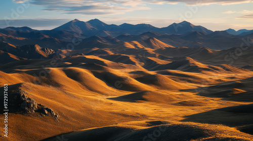 Golden light on the Mongolian mountains at dawn, casting long shadows across the rugged terrain,