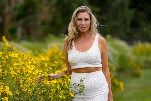 Blonde Model Radiates Grace in Vibrant Yellow Flower Field, Bathed in Late Summer Glow