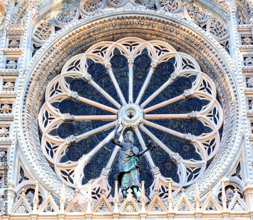 Fototapeta premium large, richly worked marble rose window with bronze statue of a saint, in an Italian Catholic church