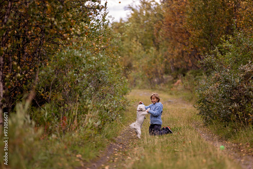 Cute little blond child, boy, training his little pet dog to obey orders, playing with him outdoors