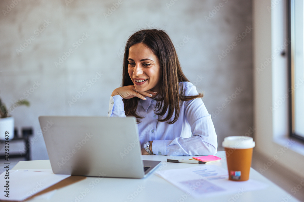 Smiling Woman Working Remotely on Laptop in a Bright Office Smiling Woman Working Remotely on Laptop in a Bright Office