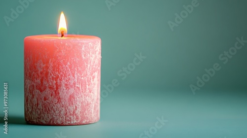 Photograph of a bright pink candle against an isolated light grayish teal background.  photo