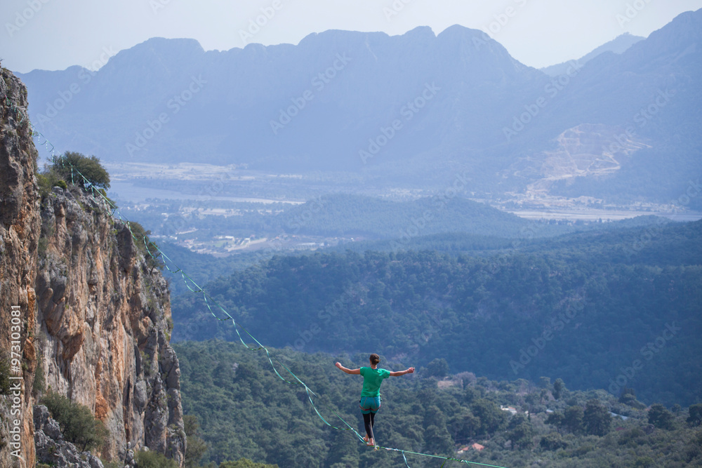 Obraz premium A tightrope walker walks along a cable stretched over a canyon.
