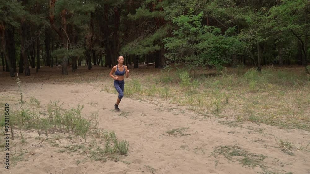 Adult woman is cardio sport and running in coniferous forest. Health jogging of fitness girl is training outdoor. Concept of workouts running and healthy lifestyle. Track path of athletic young adult. Adult woman is cardio sport and running in coniferous forest. Health jogging of fitness girl is training outdoor. Concept of workouts running and healthy lifestyle. Track path of athletic young adult.