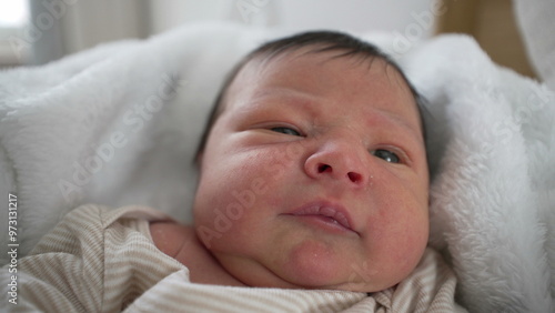 Newborn baby lying on a soft blanket, with a focused, peaceful expression. baby's delicate features, capturing a serene moment of early life