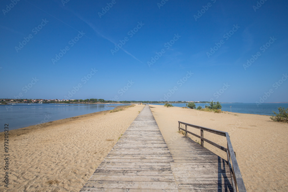 A beach surrounded by the sea on both sides. In the middle a wooden footbridge runs along the sandy beach. Natural spectacle of a Mediterranean landscape, Plaža Ždrijac, Nin, Zadar, Dalmatia, Croatia A beach surrounded by the sea on both sides. In the middle a wooden footbridge runs along the sandy beach. Natural spectacle of a Mediterranean landscape, Plaža Ždrijac, Nin, Zadar, Dalmatia, Croatia