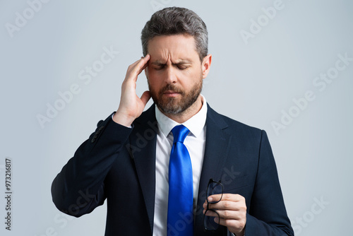 Man with headache on isolated gray studio background. Man feel pain rubbing dry eyes fatigued from work. Stressed man suffer from headache bad vision sight problem. Deadline and stressed job.