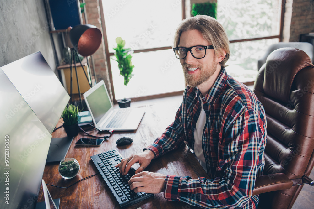 Photo system administrator young blond hair guy at loft design modern office in front of computer coding using keyboard and modern monitors Photo system administrator young blond hair guy at loft design modern office in front of computer coding using keyboard and modern monitors