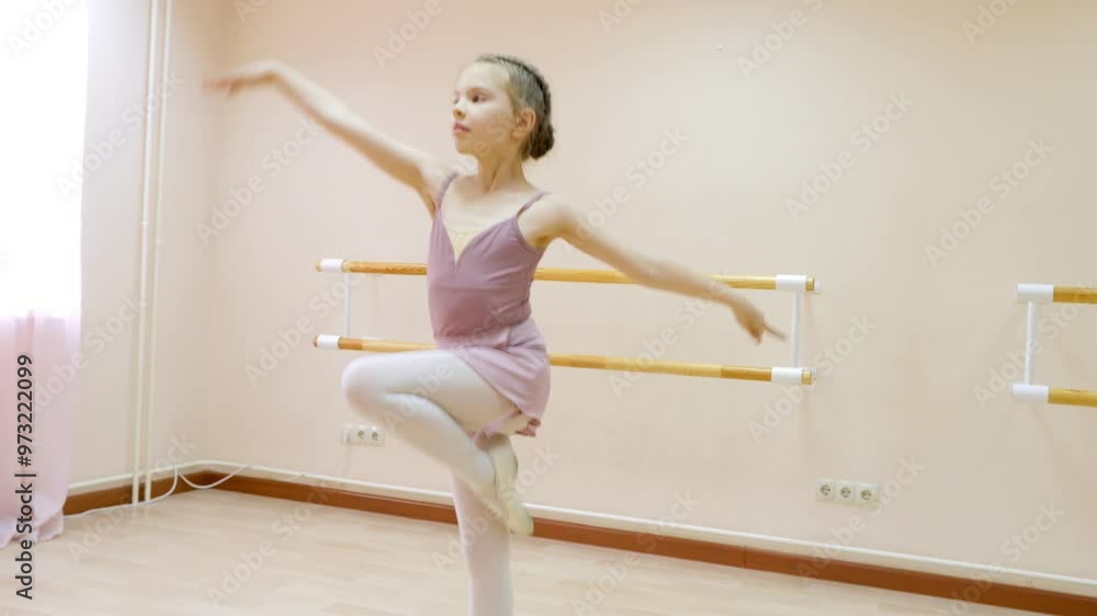 A young ballet dancer is diligently practicing her movements at the barre in the studio A young ballet dancer is diligently practicing her movements at the barre in the studio