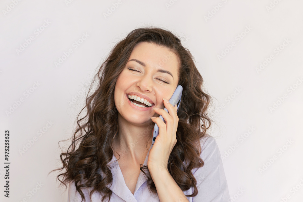 Happy young Caucasian brunette business woman with curly hair wearing a purple blouse laughing and talking on the smartphone. Mobile communication. Happy young Caucasian brunette business woman with curly hair wearing a purple blouse laughing and talking on the smartphone. Mobile communication.